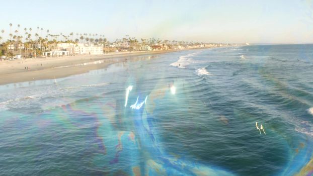 Blowing soap bubbles on ocean pier in California, blurred summertime background. Creative romantic metaphor, concept of dreaming happiness and magic. Abstract symbol of childhood, fantasy, freedom.