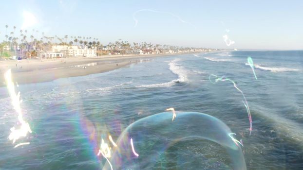 Soap bubbles on pier in California, blurred summertime seamless looped background. Creative romantic metaphor, concept of dreaming, happiness and magic. Abstract symbol of childhood, fantasy, freedom.