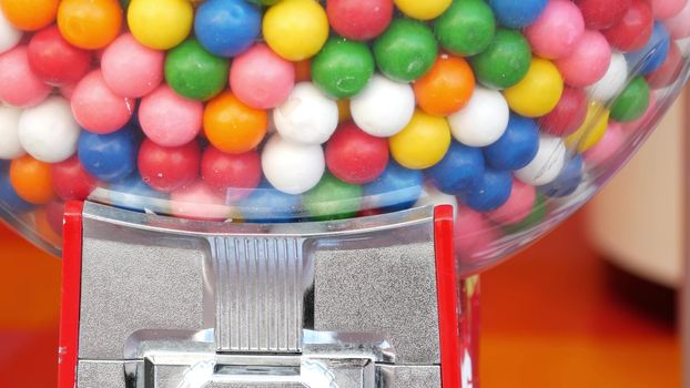 Colorful gumballs in classic vending machine, USA. Multi colored buble gums, coin operated retro dispenser. Chewing gum candies as symbol of childhood and summertime. Mixed sweets in vintage automate.