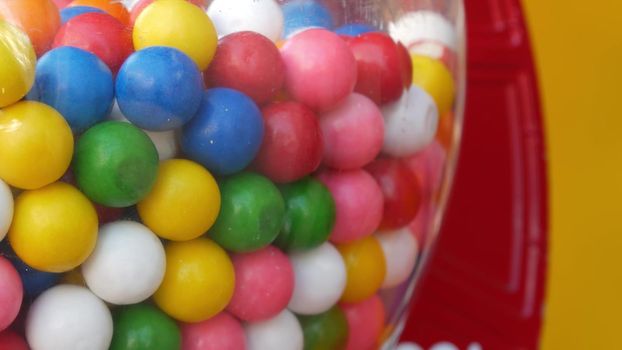 Colorful gumballs in classic vending machine, USA. Multi colored buble gums, coin operated retro dispenser. Chewing gum candies as symbol of childhood and summertime. Mixed sweets in vintage automate.