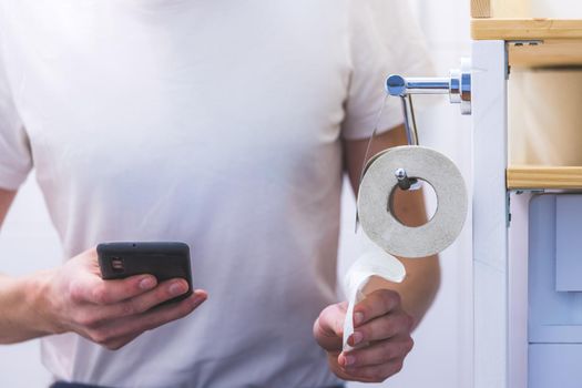 Close up of young man using his smartphone while sitting on the toilet