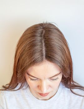 A woman's head with a parting of gray hair that has grown roots due to quarantine. Brown hair on a woman's head close-up.