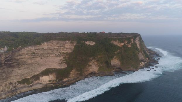 aerial view rocky ocean coastline at sunset. seascape waves break on rocky shore travel concept.