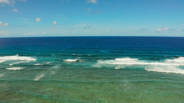 Seascape: blue ocean and surf waves crashing on a coral reef top view. Summer and travel vacation concept
