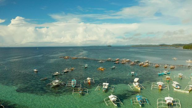 Tourist boats moored to a long pier on a tropical island, General Luna, Siargao.