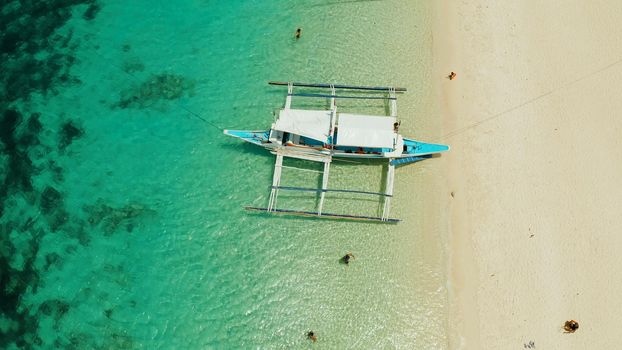 Tropical white sand beach, near the blue lagoon and corall reef from above, Boracay, Philippines. Sandy beach with tourists. Summer and travel vacation concept.