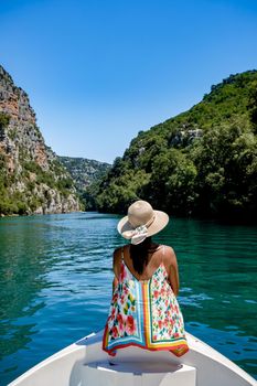 cliffy rocks of Verdon Gorge at lake of Sainte Croix, Provence, France, Provence Alpes Cote d Azur, blue green lake with boats in France Provence. Europe, young woman in peddle boat looking at river