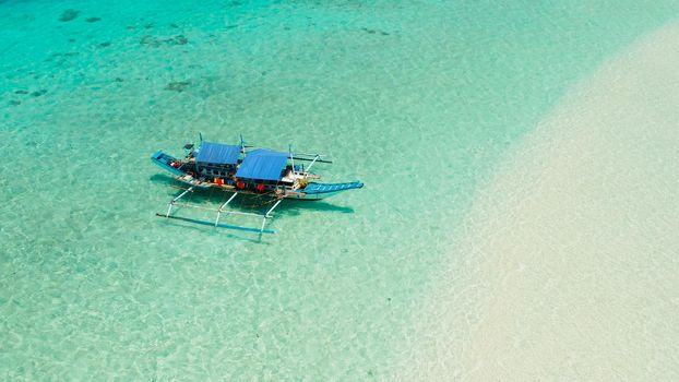 Boat on a tropical beach in the turquoise water of the lagoon from above. Summer and travel vacation concept. Mansalangan sandbar. Beach at the atoll. Balabac, Palawan, Philippines.