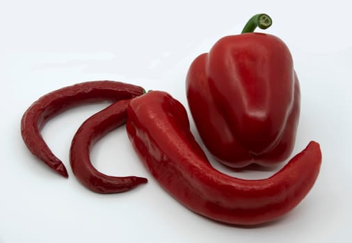 Ripe juicy red peppers with capi and hot red peppers on a white background.