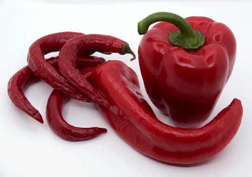 Ripe juicy red peppers with capi and hot red peppers on a white background.