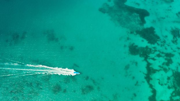 Tourist boats on the surface of the turquoise lagoon, aerial view. Seascape with beach on tropical island. Summer and travel vacation concept. Boracay Island, Philippines