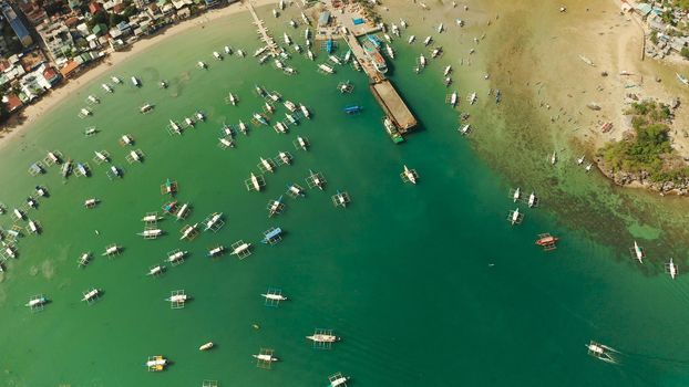 Many boats in the turquoise lagoon near city El nido. Seascape with blue bay and boats view from above. Palawan, Philippines. traditional Filipino wooden outrigger boat called a banca. Summer and travel vacation concept