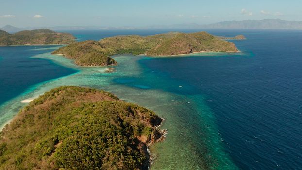 Tropical islands with blue lagoons, coral reef and sandy beach, aerial view. Palawan, Philippines. Islands of the Malayan archipelago with turquoise lagoons.
