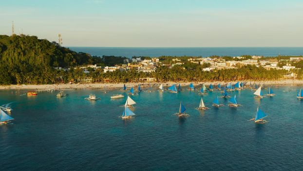 Topical white beach from above at sunset with tourists and hotels and sailing boats on Boracay Island. Tropical white beach with sailing boat. Summer and travel vacation concept.