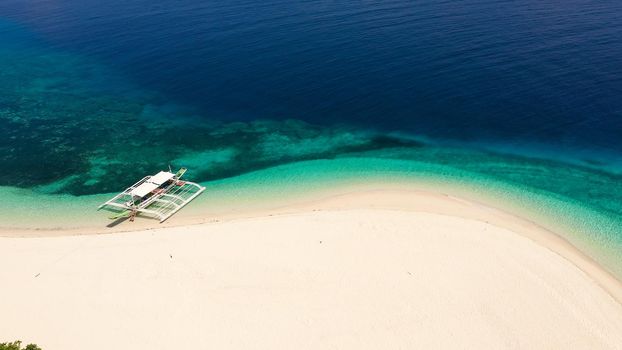 Tropical beach of white sand, top view. Tourist boat off the coast. Blue sea with turquoise lagoons. Summer and travel vacation concept. Tranquil beach scene.