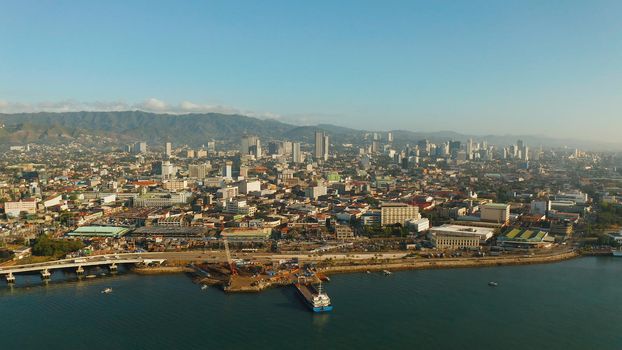 Aerial view of panorama of Cebu city with skyscraper, buildings and seaport with ships and ferries in the early morning. Philippines.