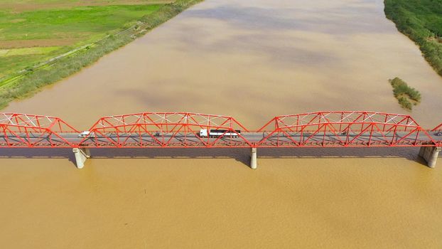 Bridge over the Cagayan River, Philippines, aerial view. Road bridge over a wide river. Cars ride on the bridge. Landscape, agricultural fields near the river.
