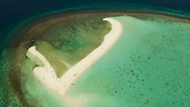 Tropical white island and sandy beach with tourists surrounded by coral reef and blue sea, aerial view. Sandbar Atoll. Island with sand bar and coral reef. Summer and travel vacation concept, Camiguin, Philippines.