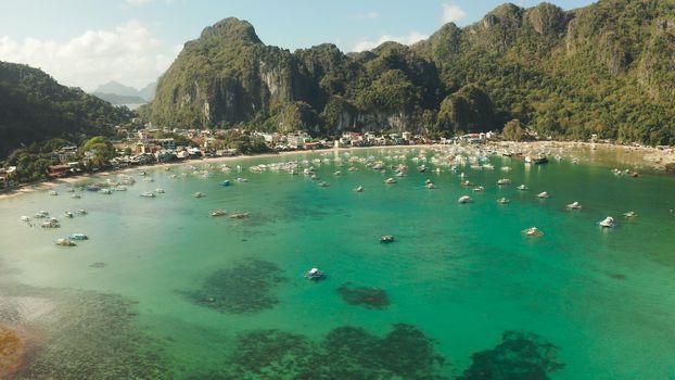 Many boats in the turquoise lagoon near city El nido, aerial view. Seascape with blue bay and boats view from above. Palawan, Philippines. traditional Filipino wooden outrigger boat called a banca. Summer and travel vacation concept