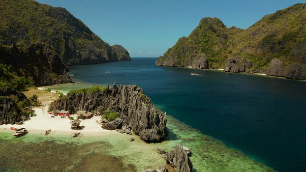 Tropical landscape bay with beach and clear blue water surrounded by cliffs, aerial drone. El nido, Philippines, Palawan. Seascape with tropical rocky islands, ocean blue water. Summer and travel vacation concept