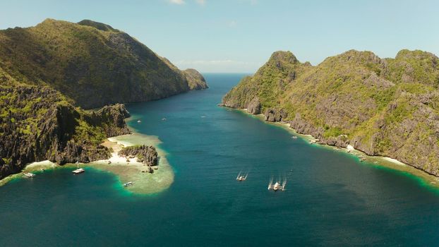 Tropical landscape bay with beach and clear blue water surrounded by cliffs, aerial drone. El nido, Philippines, Palawan. Seascape with tropical rocky islands, ocean blue water. Summer and travel vacation concept