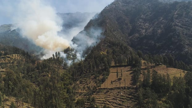 fire in mountain forest. aerial view forest fire and smoke on slopes hills. wild fire in mountains in tropical forest, Java Indonesia. natural disaster fire in Southeast Asia