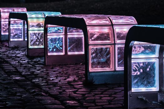 Luminous colorful glass bench in a dark night