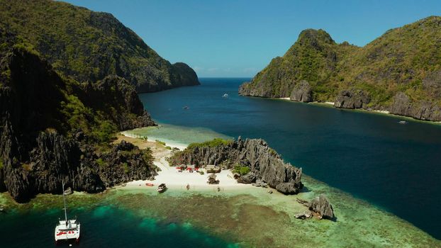 Tropical landscape bay with beach and clear blue water surrounded by cliffs, aerial drone. El nido, Philippines, Palawan. Seascape with tropical rocky islands, ocean blue water. Summer and travel vacation concept