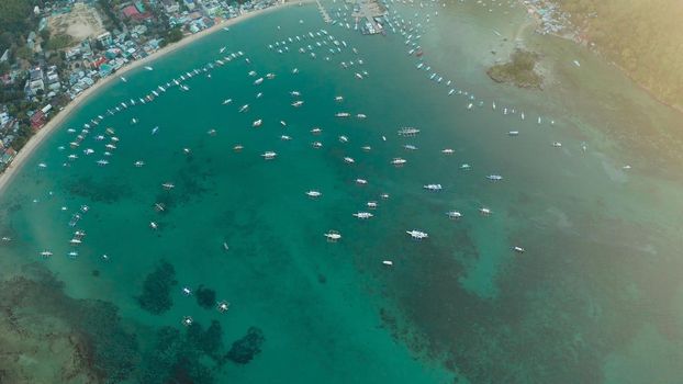 Many boats in the turquoise lagoon at sunset. Seascape with blue bay and boats view from above. El nido, Palawan, Philippines. traditional Filipino wooden outrigger boat called a banca. Summer and travel vacation concept