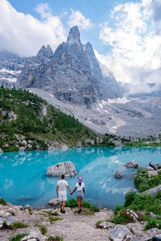 Beautiful Lake Sorapis Lago di Sorapis in Dolomites, popular travel destination in Italy. Blue green lake in Italian Dolomites. Couple hiking in the Dolomites Italy