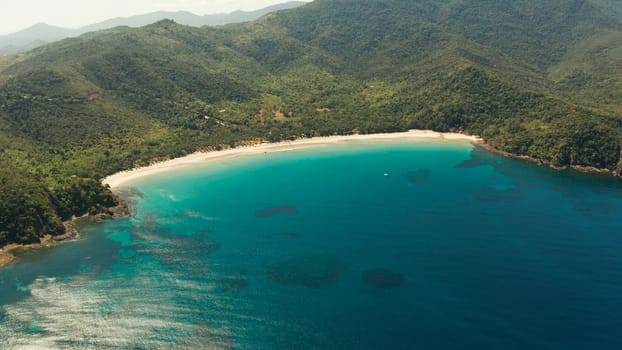 Aerial view beautiful tropical beach Nagtabon in the cove with blue lagoon and turquoise water surrounded by rainforest. Palawan, Philippines. tropical landscape. Seascape island and clear blue water. Summer and travel vacation concept