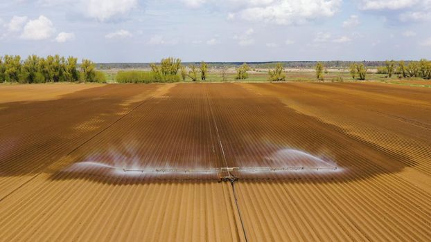 aerial view crop irrigation machine using center pivot sprinkler system. An irrigation pivot watering agricultural land. Irrigation system watering farm land.