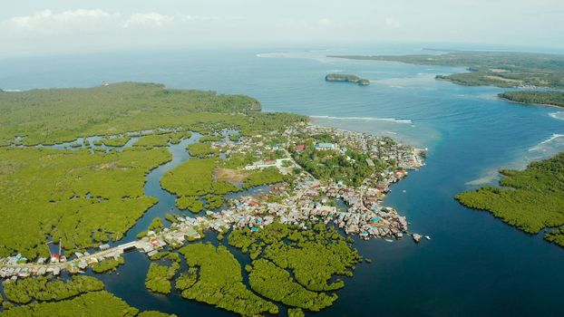 Town in wetlands and mangroves on the ocean coastline from above. Siargao island, Philippines.