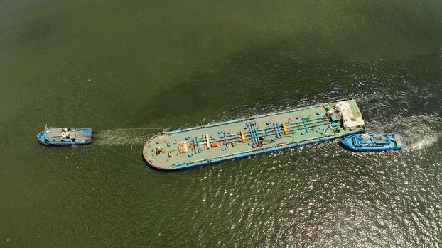Tugs pulling heavy barge on the river top view. Tugs and cargo ship on the river.