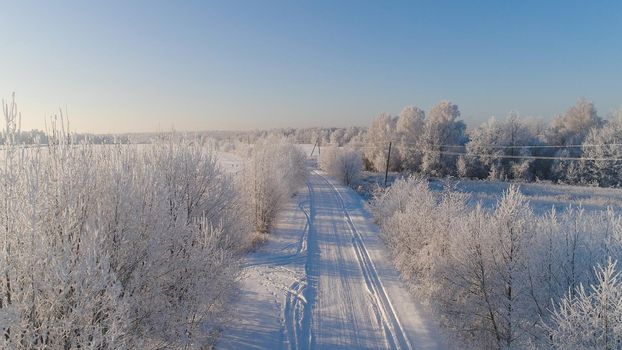 aerial view winter landscape countryside road through winter field with forest. winter forest on sunny day. winter in countryside
