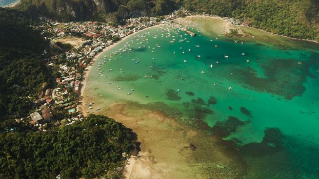 Many boats in the turquoise lagoon near city El nido. Seascape with blue bay and boats view from above. Palawan, Philippines. traditional Filipino wooden outrigger boat called a banca. Summer and travel vacation concept