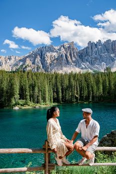 The majestic Lake of Lago di Carezza, beautiful green and turquoise colors in Dolomites mountains Italy,South tyrol, Italy. Landscape of Lake Carezza or Karersee couple men woman hiking