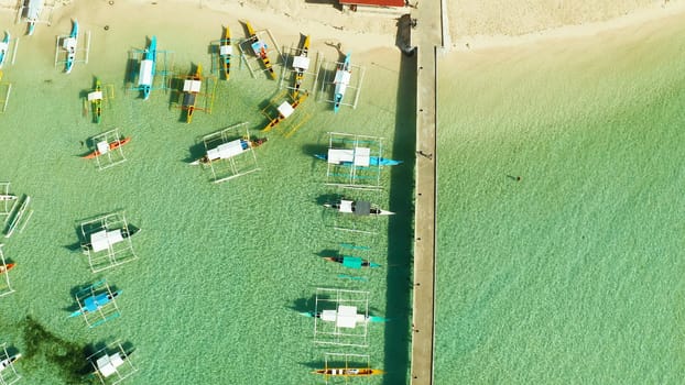 Boats on the tropical beach at the long pier awaiting tourists, General Luna, Siargao.