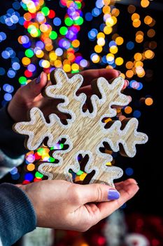 Holding Christmas snowflake decoration isolated on background with blurred lights. December season, Christmas composition.