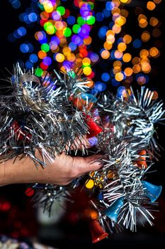 Holding Christmas garland decoration isolated on background with blurred lights. December season, Christmas composition.