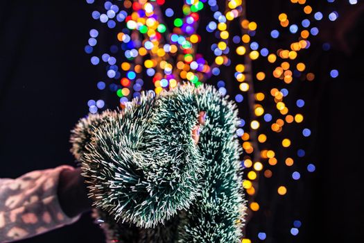 Holding Christmas garland decoration isolated on background with blurred lights. December season, Christmas composition.