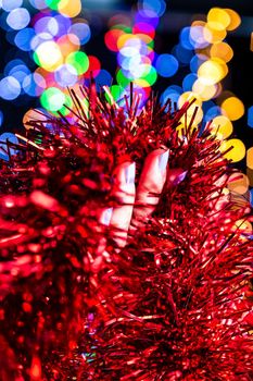 Holding Christmas garland decoration isolated on background with blurred lights. December season, Christmas composition.