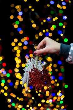 Woman's hands hold christmas decoration. Christmas and New Year holidays background, winter season with Christmas ornaments and blurred lights