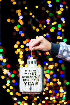 Woman's hands hold christmas decoration. Christmas and New Year holidays background, winter season with Christmas ornaments and blurred lights