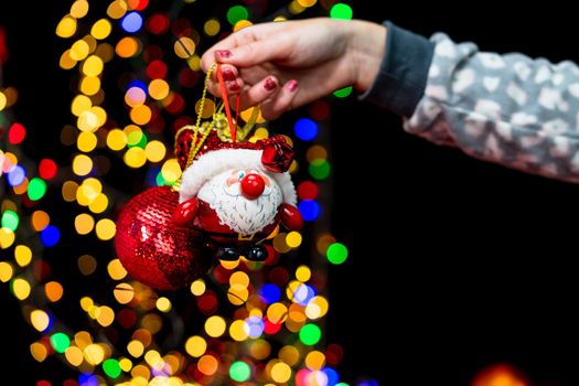 Woman's hands hold christmas decoration. Christmas and New Year holidays background, winter season with Christmas ornaments and blurred lights