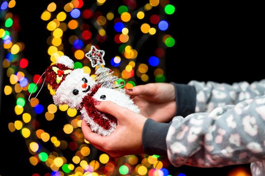 Woman's hands hold christmas decoration. Christmas and New Year holidays background, winter season with Christmas ornaments and blurred lights