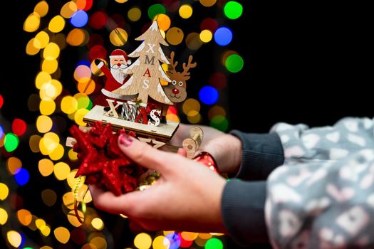 Woman's hands hold christmas decoration. Christmas and New Year holidays background, winter season with Christmas ornaments and blurred lights