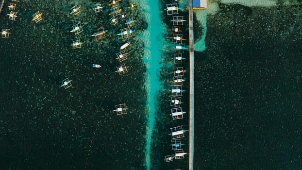 Long pier with moored boats in the morning, aerial view. General Luna, Siargao island.