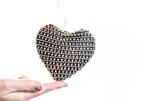 Hand holding heart shaped decoration isolated on white.