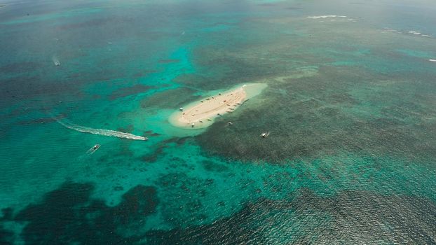 Tropical white island and sandy beach with tourists surrounded by coral reef and blue sea, aerial view. Naked Island, Siargao. Summer and travel vacation concept